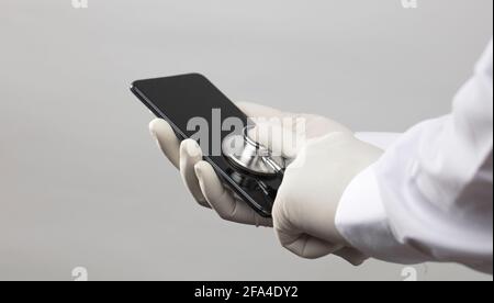 mobile technician, with stethoscope on mobile screen, diagnosis and repair, white background Stock Photo