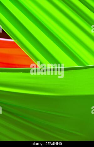 Bolts of green and orange fabric drying in the sun just after dyeing as abstract background Stock Photo
