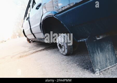 Abandoned car with broken wheels on the street Stock Photo