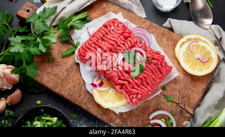 Raw minced meat with spices, vegetables and herbs on dark background. Ingredients for cooking concept. Stock Photo