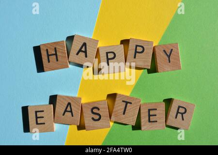 Happy Easter, words in wooden alphabet letters isolated on colourful background Stock Photo