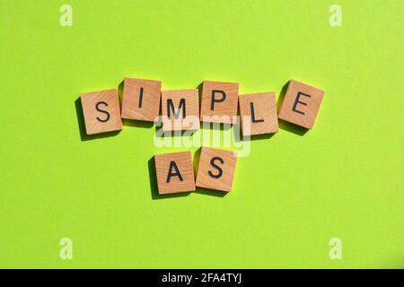 Simple As, words in wooden alphabet letters isolated on bright green background Stock Photo