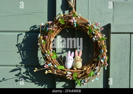 Easter Wreath with two bunnies, hanging on an old green door Stock Photo
