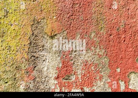 Shabby painted cement plastered wall. Weathered corrosive surface. Abstract background. Red and yellow Stock Photo