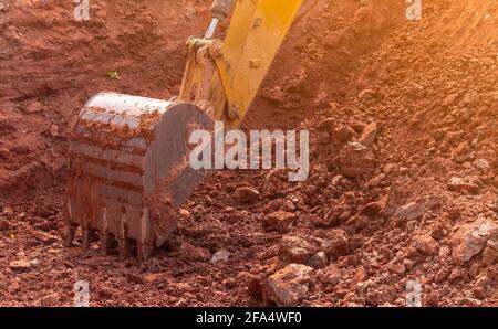 Backhoe working by digging soil at construction site. Bucket of backhoe digging soil. Crawler excavator digging on dirt. Closeup backhoe bucket. Stock Photo