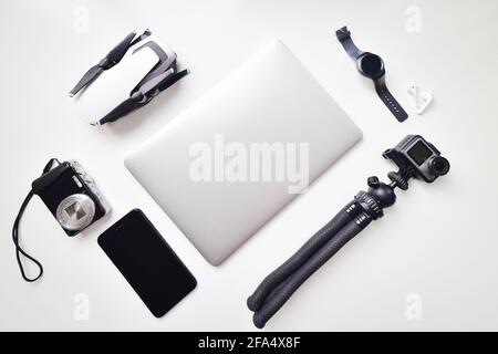 Flat lay daily vlogging lightweight gadget travel set up isolated on white table background: compact camera, phone, watch, compact camera, drone, note Stock Photo