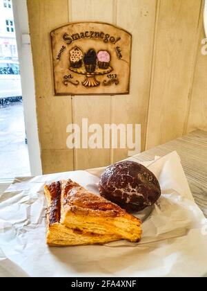 Assorted fresh pastries and a glazed donut on paper on a wood-panel bakery counter Stock Photo