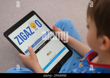 Zigazoo app website login screen seen on ipad which is in the hands of a young child. New app is a safe platform for children also called as 'Tiktok f Stock Photo