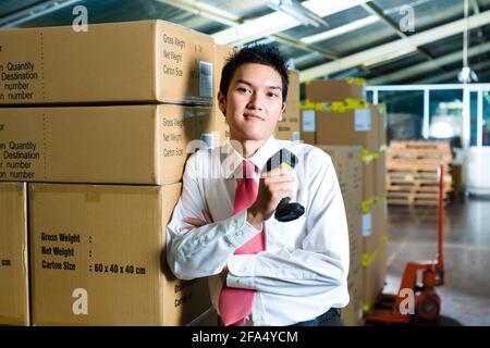 Young man in a suit with a bar code scanner in a warehouse Stock Photo