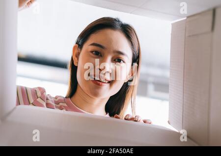 Young Asian woman opens the new package that has been sent home Stock Photo