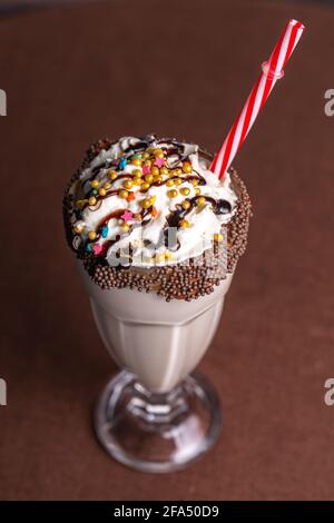 sweet milkshake with a tube on a brown background. Stock Photo