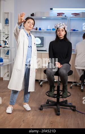 Brain scientis and patient in laboratory looking at virtual display using high tech medical science. Scientists working with healthcare simulator. Neurology physician analysing brain scan. Stock Photo