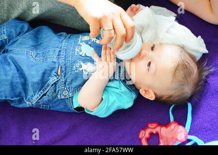 POZNAN, POLAND - Jan 31, 2016: Baby drinking from a plastic bottle Stock Photo