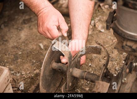 farmer prepares field plowing machine for work on farmland soil in spring Stock Photo