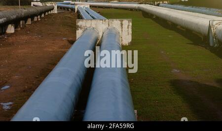 Elevated Heat Pipes. Pipeline above ground, conducting heat to heat city. Urban line in metal insulation in residential quarter of city. Stock Photo