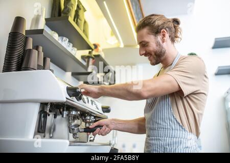 Knowledgeable man cleaning filter of coffee machine Stock Photo