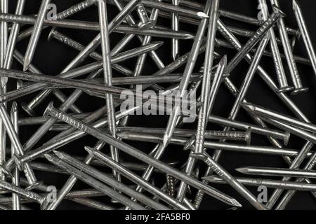 A structure consisting of new shiny nails on a dark background. Stock Photo