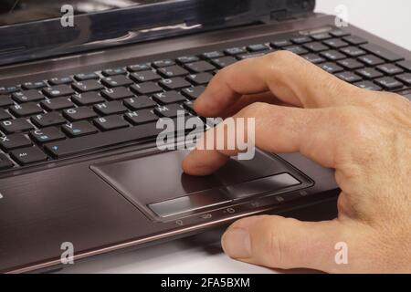 A man's hand operating a laptop with the help of a touchpad. Stock Photo