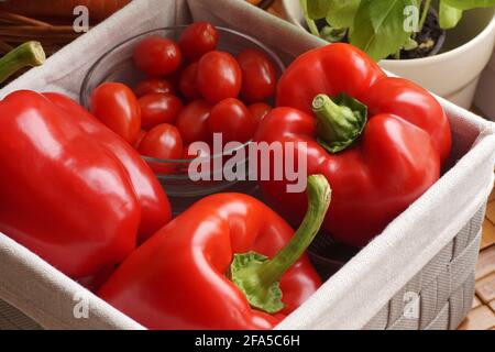 A kitchen basket filled with vegetables. Peppers, tomatoes and basil in a pot. Stock Photo