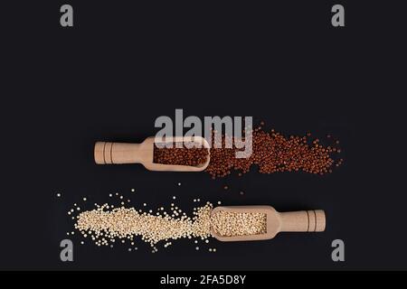 Raw organic Red and white quinoa grains in wooden spoons on black background. Gluten free ancient grain. Healthy diet. Stock Photo