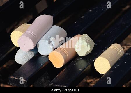Colorful chalk sticks on park bench. Kids drawing chalks. Pavement art material. Outdoors. Stock Photo