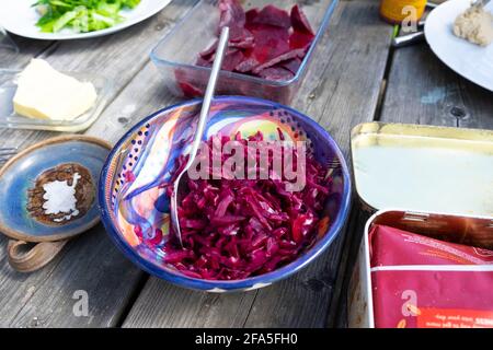 Grated beetroot salad next to sliced beetroot beets in a bowl on a wooden picnic table outside at lunch in Carmarthenshire Wales UK   KATHY DEWITT Stock Photo