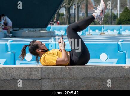 A fit woman pauses from her workout routine to check her phone. In Queens, New York City Stock Photo