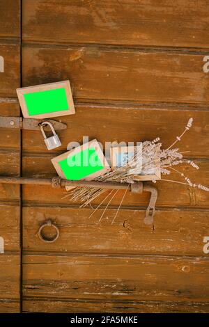 Blank portraits and a bouquet of wildflowers on the background of a beautiful wooden door with a bolt Stock Photo