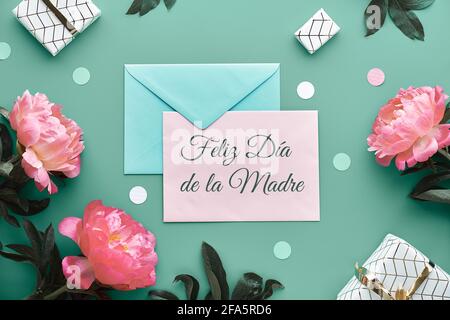 Feliz Dia de la Madre means Happy Mother's Day in Spanish. Pink peony flowers, wrapped gifts tied with gold ribbon. Mint green, pink floral Stock Photo