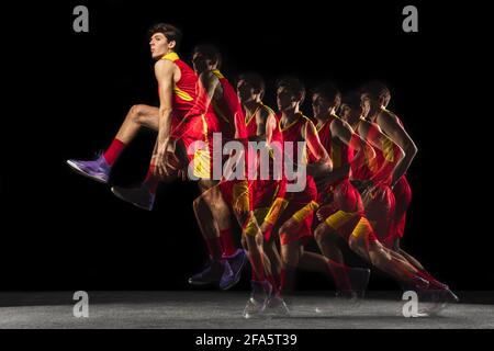 Young caucasian basketball player in motion and action in mixed light on dark background. Concept of healthy lifestyle, professional sport, hobby. Stock Photo
