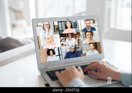 Group of diverse people involved in video conference on the laptop screen. Female using computer app for video connection with multiracial team, discussing online, teamwork on the distance Stock Photo