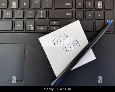 A White sticky note with text BIG IDEA and pen on top of laptop keyboard Stock Photo