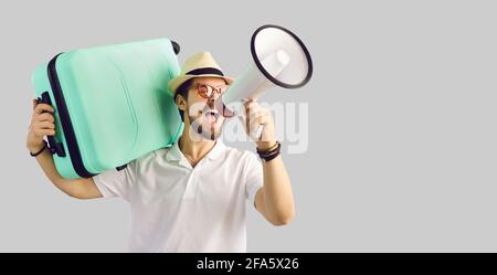 Young tourist man in summer hat with luggage suitcase screaming on megaphone Stock Photo