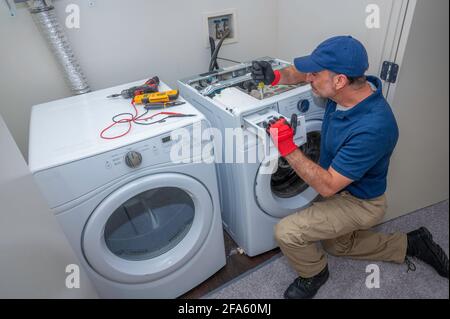 Appliance technician working on a front load washing machine in a laundry room Stock Photo