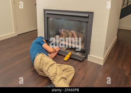 Service technician working on a gas fireplace inside of a residential home Stock Photo
