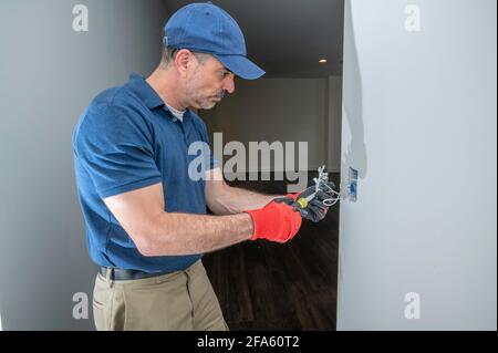 Electrician working on a low voltage toggle switch in a hallway Stock Photo