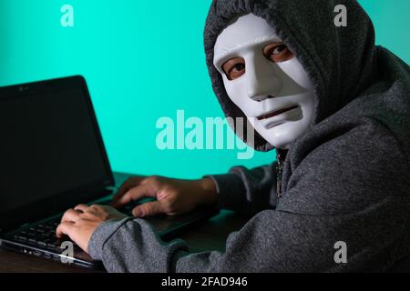 Thief hacker in mask stealing personal information from laptop. Concept hacking. Stock Photo