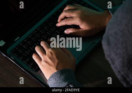 Thief hacker in mask stealing personal information from laptop. Concept hacking. Stock Photo