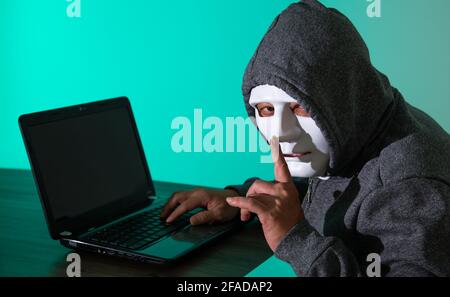 Thief hacker in mask stealing personal information from laptop. Concept hacking. Stock Photo