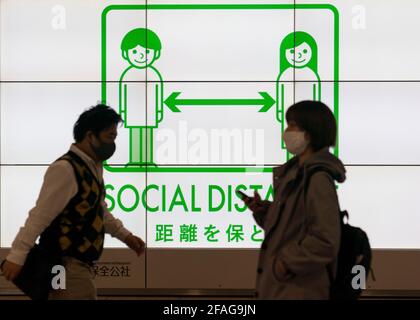 Tokyo. 23rd Apr, 2021. People walk past a social distancing signage in Tokyo, Japan on April 23, 2021. Japan's Prime Minister Yoshihide Suga on Friday declared a third state of emergency over COVID-19 in Tokyo, Osaka, Kyoto and Hyogo. The state of emergency will come into effect from Sunday to May 11. Credit: Christopher Jue/Xinhua/Alamy Live News Stock Photo