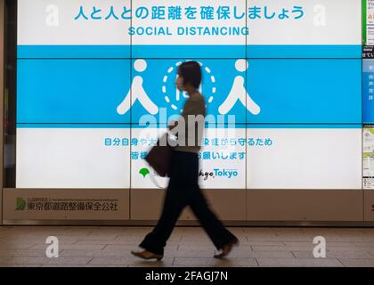 Tokyo. 23rd Apr, 2021. A woman walks past a social distancing signage in Tokyo, Japan on April 23, 2021. Japan's Prime Minister Yoshihide Suga on Friday declared a third state of emergency over COVID-19 in Tokyo, Osaka, Kyoto and Hyogo. The state of emergency will come into effect from Sunday to May 11. Credit: Christopher Jue/Xinhua/Alamy Live News Stock Photo