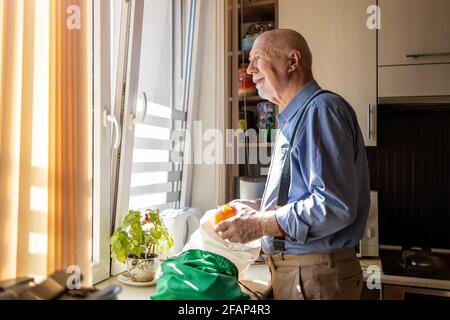 Senior Man Looking Through Window at Home Stock Photo