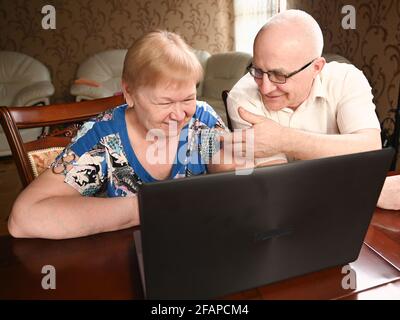Portrait of happy old senior couple with laptop computer having video call chat. Retirement senior couple old age lifestyle communicating technology c Stock Photo