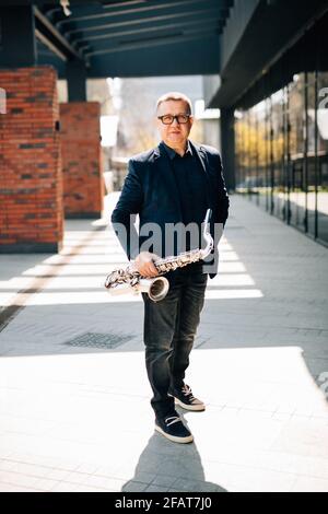 Middle aged english street musican playing on saxophone Stock Photo