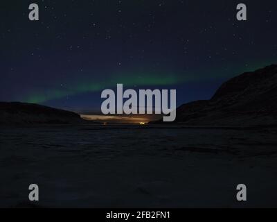 Beautiful bow of green shimmering northern light (aurora borealis) in the dark, starry night sky above Snæfellsnes, Iceland in winter season. Stock Photo