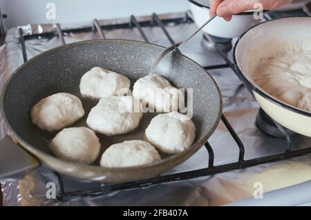 Yeast pancakes are fried in oil in frying pan on stove Stock Photo