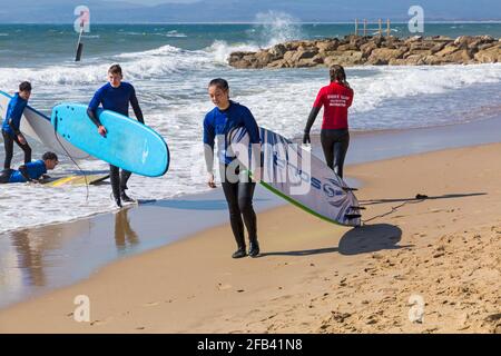 Surfers at Branksome Dene Chine, Poole, Dorset UK on a warm sunny day in April Stock Photo