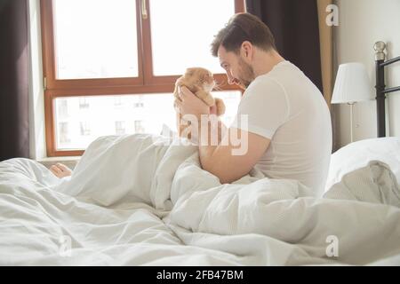 man resting in bed with ginger cat, friends, real life Stock Photo