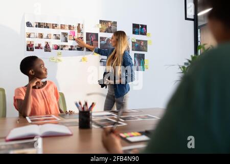 Diverse group of business colleagues brainstorming looking at photos in meeting room Stock Photo