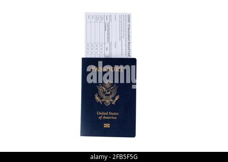US Passport with Covid 19 vaccination record card placed inside of book isolated on white background.  Individual record for use during the covid 19 c Stock Photo